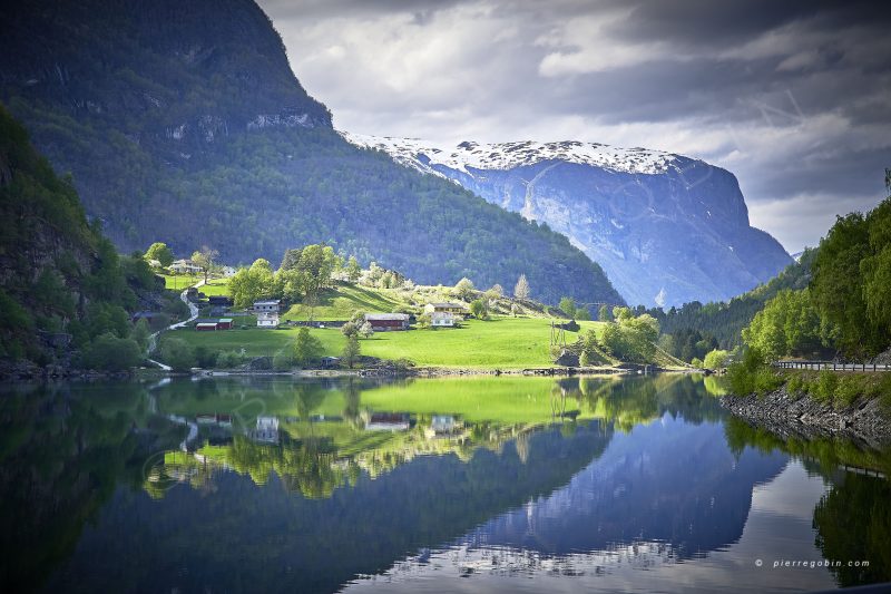 Majestueux fjord verdoyant en Norvege avec les reflets du village dans le lac